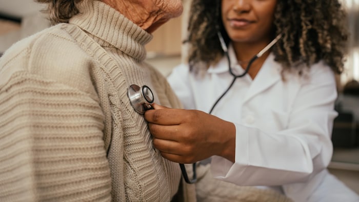Une professionnelle de la santé écoute le coeur d'une aînée.