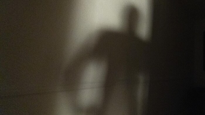  La silhouette d'un homme se dessine dans le cadre d'une porte