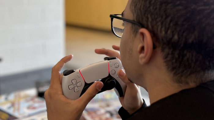 Yahya Chatri tient une manette de jeux vidéo en main.