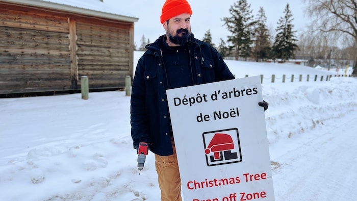 Un employé de la Ville de Winnipeg tient une pancarte du festival du voyageur.