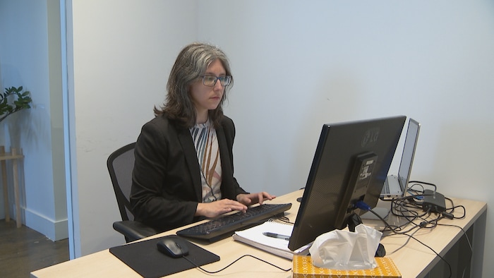 Sara Eve Levac assise à son bureau devant ses écrans d’ordinateur.