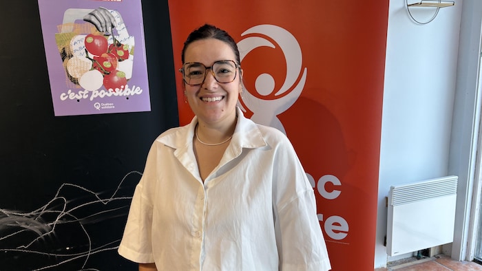 Sara Germain pose devant une bannière de son parti.