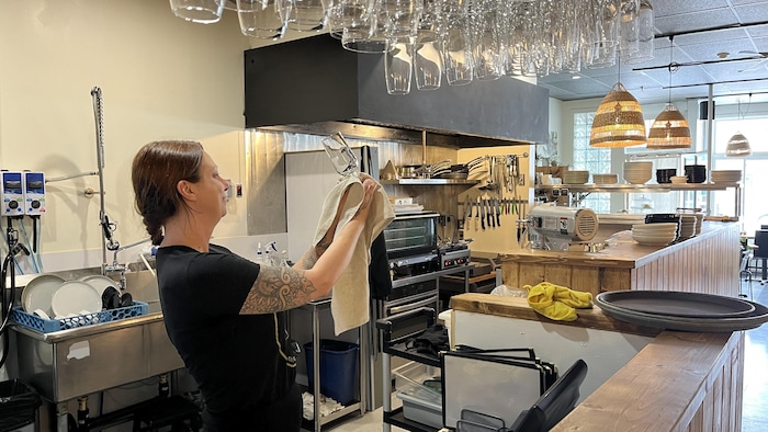 Sara Tremblay essuie un verre dans son restaurant.