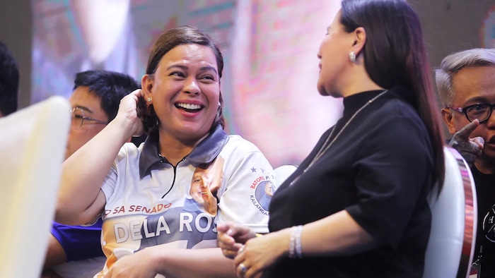 Nakaupo si Sarah Duterte-Carpio kasama ang ilang tao sa entablado.
