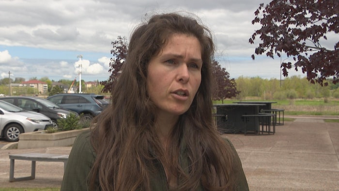 Une femme en entrevue à l'extérieur, près d'un stationnement.