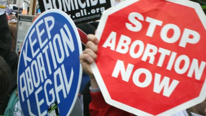Un panneau bleu indiquant «Gardez l'avortement légal» et l'autre rouge disant «Arrêtez les avortements maintenant» 
