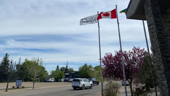 À Warman, des drapeaux flottent devant l’hôtel de ville sous un ciel nuageux.