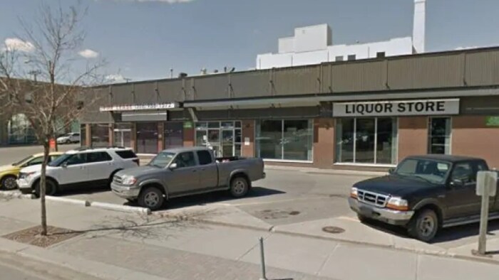 Un stationnement avec des véhicules et un magasin de vente d'alcool.