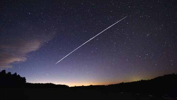 Un satellite laisse une trace lumineuse dans l'espace aérien pendant la nuit.
