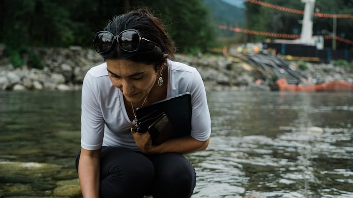 Kate Tairyan examine un poisson mort sur les berges de d'une rivière.