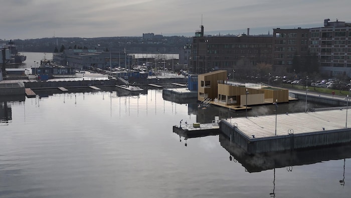Une maquette 3D de quatre saunas sur une plateforme flottante au bassin Louise à Québec vue en hauteur.