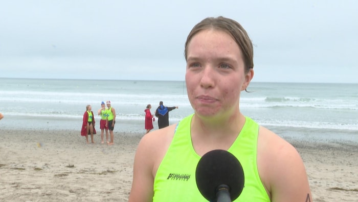 Une jeune athlète sur la plage, devant les vagues. 