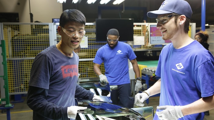 Des travailleurs chinois et américains en plein travail dans une usine de vitres d'automobiles.
