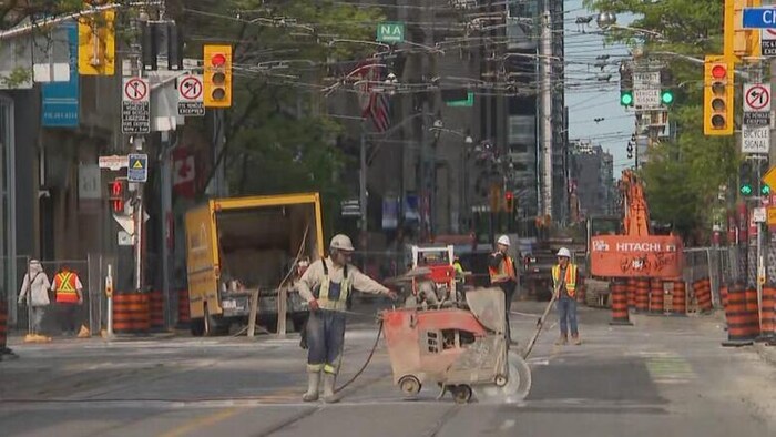 Un ouvrier avec une grosse machine qui découpe le béton.