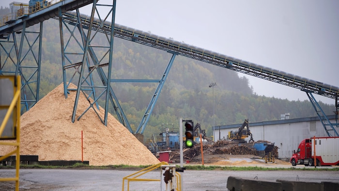 Imposante montagne de résidus de bois et de poussière de bois sous la structure extérieure de la scierie Rivière-aux-Rats.