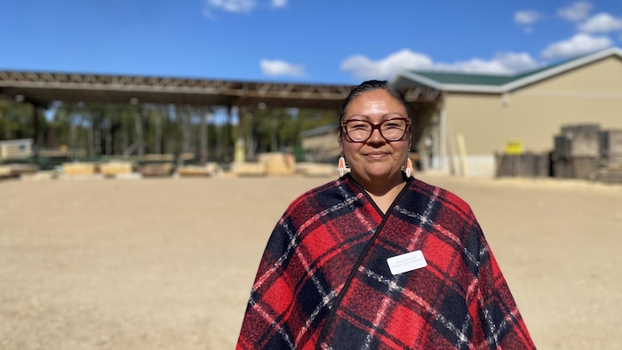 Alys Quoquochi souriante dans une cour à bois.