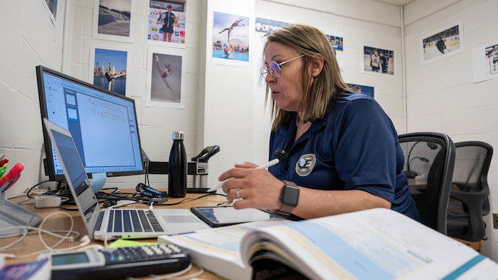 Une enseignante est assise à un bureau devant un ordinateur portable.