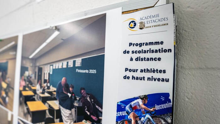 Un dépliant du programme est épinglé sur un babillard à côté de la photo d’une classe.