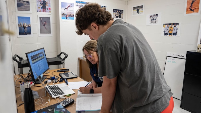 Une enseignante est assise à un bureau devant un ordinateur portable.