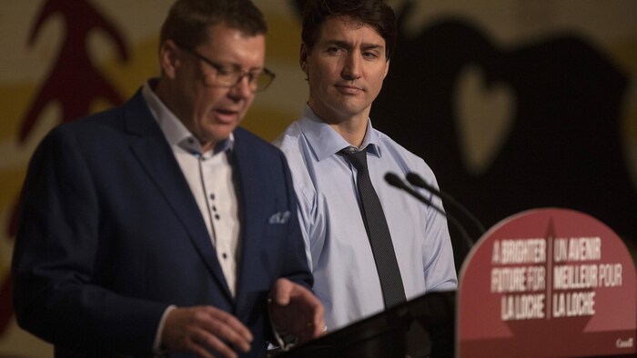 Scott Moe en bid     de faire un discours. En arrière-plan, Justin Trudeau le regarde.