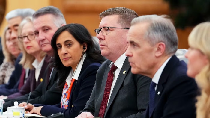 Scott Moe assis à une table avec Mark Carney et d'autres représentants.