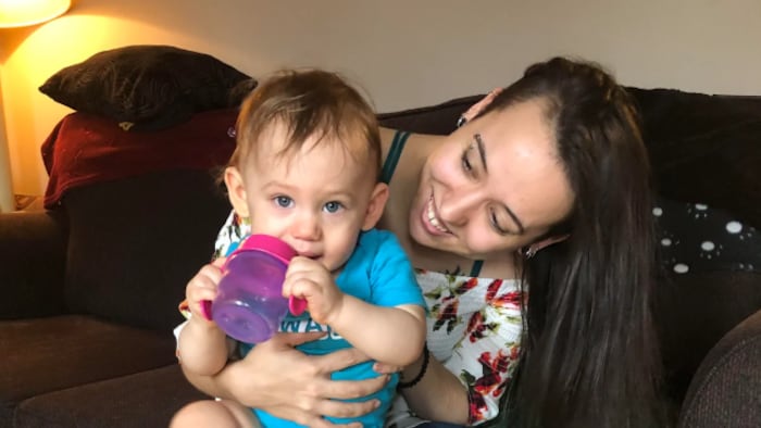 La jeune femme tient son bébé sur ses genoux.