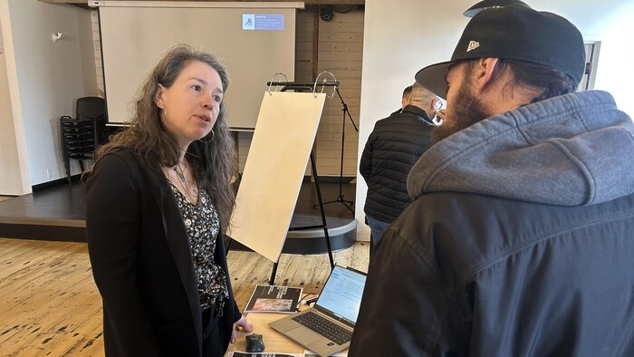 Une femme discute avec un homme, près d'une table.