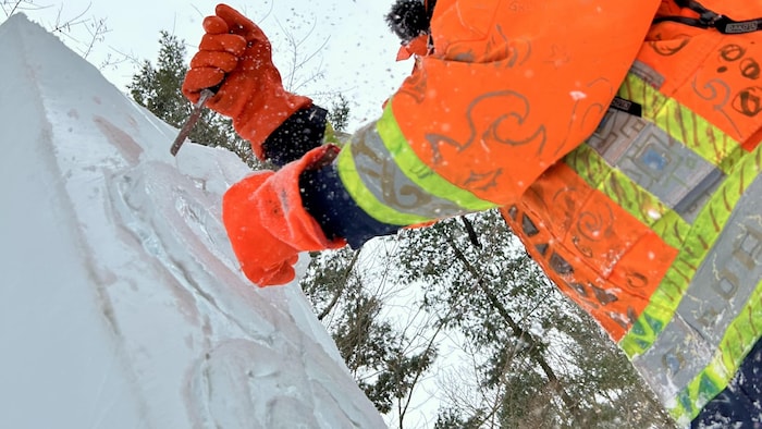 Un sculpteur de glace est à l'ouvrage.