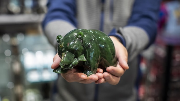 Gros plan d'une sculpture en jade d'un ours qui tient un poisson dans sa bouche.