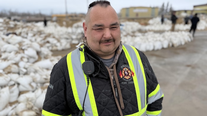 Un homme devant un tas de sacs de sable