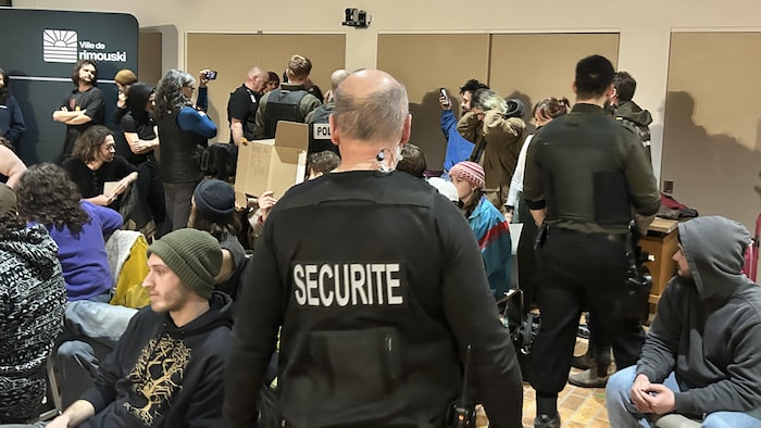 Des agents de sécurité et policiers interpellent des citoyens dans la salle du conseil. 