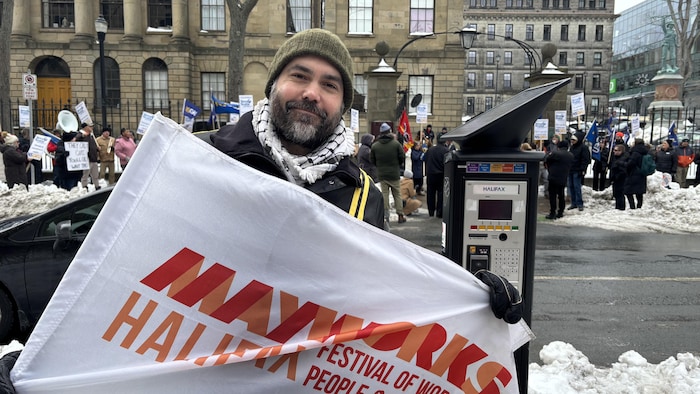 Un homme avec une grande bannière pendant une manifestation en hiver.