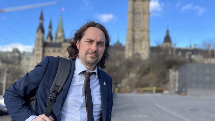 Sébastien Lemire tient son sac sur son dos devant le Parlement du Canada, à Ottawa.