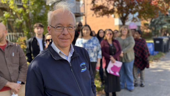 Un enseignant en avant-plan et des collègues derrière lui