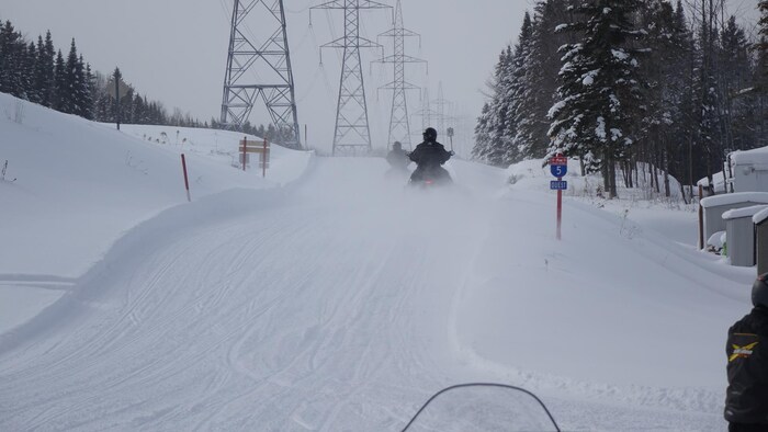 Des motoneigistes sur une piste.