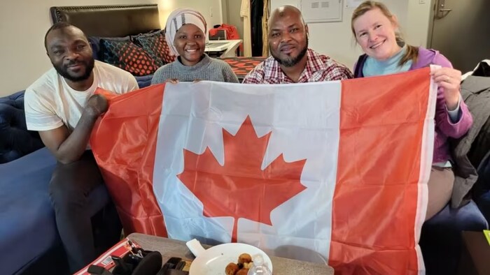Seidu Mohammed, from left, Mariam Mohammed, Razak Iyal and Laurel Martin pose with a Canadian flag to mark Seidu and Razak's steps toward becoming citizens of the country. The two women have supported the duo in making a life for themselves in Winnipeg. (Submitted)