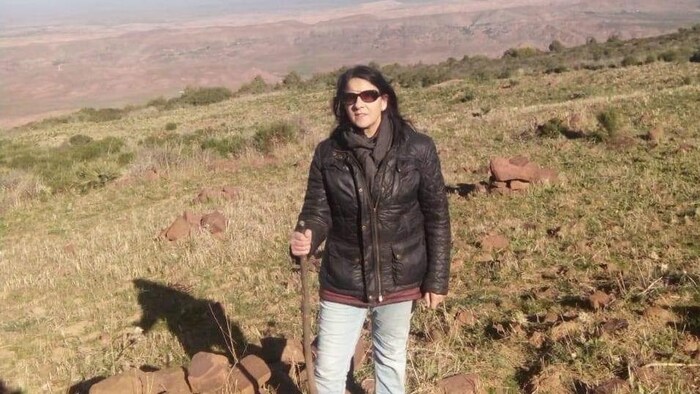 امرأة تحمل عصا وهي تمشي على جبل.