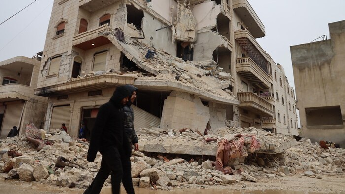Deux hommes passent devant un bâtiment fortement endommagé à la suite d'un tremblement de terre dans la ville de Zardana, dans la campagne de la province d'Idlib, au nord-ouest de la Syrie.