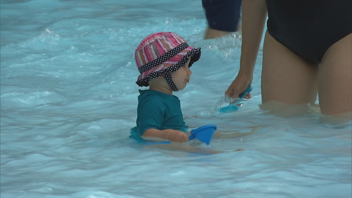 Un très jeune enfant barbotant dans une piscine.