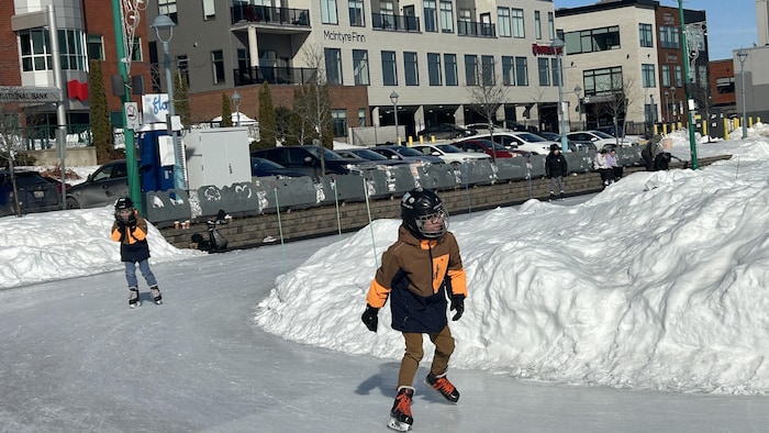 Un enfant patine sur une patinoire extérieure.
