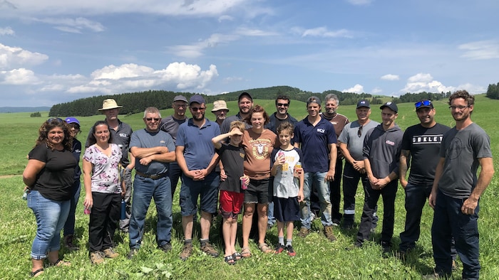 Groupe d'agriculteurs avec leurs femmes et leurs enfants posant dans un champ.