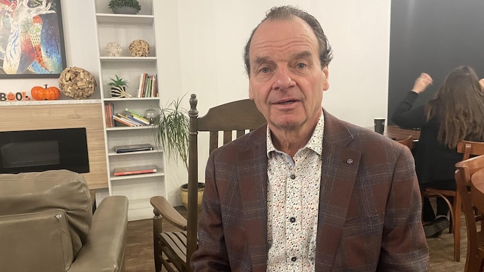 Serge Allard fixe la caméra en souriant légèrement.