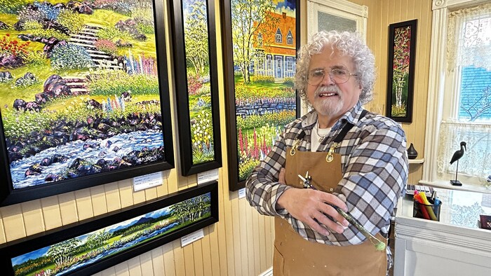 Le peintre Serge Desbiens devant des toiles de son atelier-galerie de Saint-Flavie.