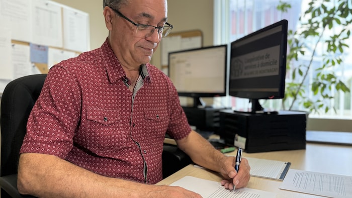 Serge Kirouac, assis à son bureau, un crayon à la main.