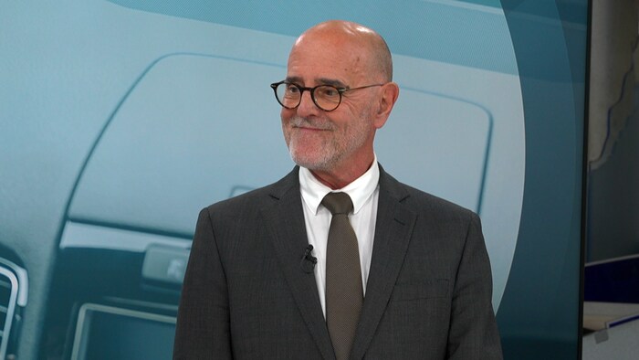 Un homme sourit sur un plateau de télé.
