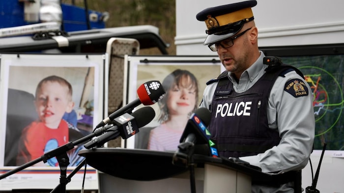 Le sergent d'état-major Curtis MacKinnon, de la GRC, devant des portraits des enfants disparus Lily et Jack Sullivan.