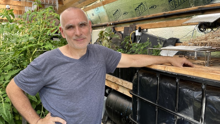 Benoît Paquette se tient debout dans la serre, près des bacs qui contiennent de l'eau.