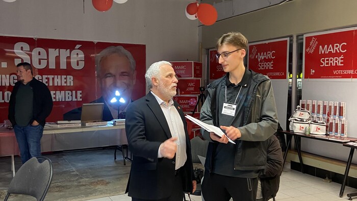 Le candidat libéral Marc G. Serré en veston noir et un membre de son équipe.