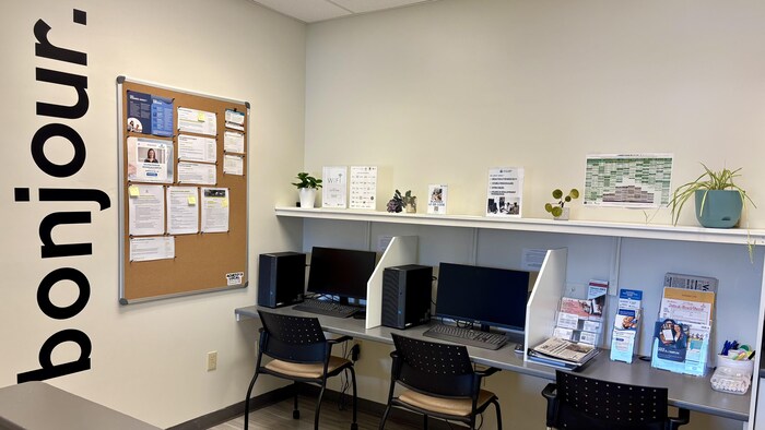 Des bureaux avec des ordinateurs et des chaises. Il y a également des pamphlets. 