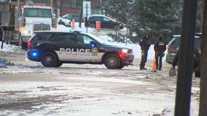 Une voiture du Service de police de la Ville de Montréal et des agents debout à côté.